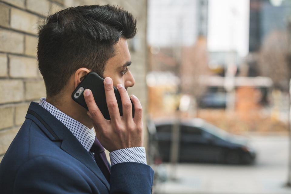 Un homme en costume, au téléphone, dans la rue